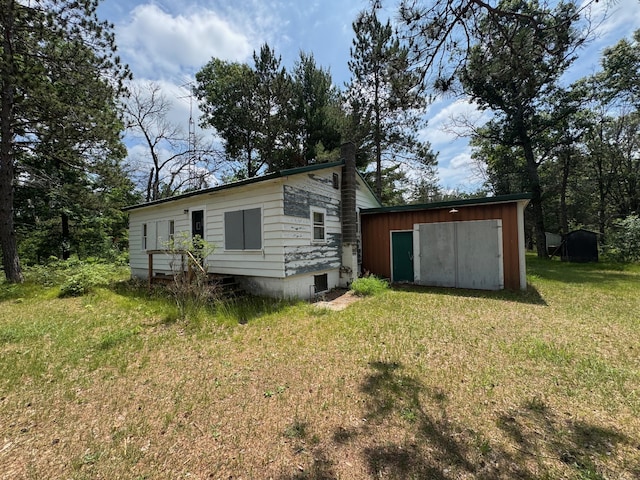4231 W 5 Mile Rd, Irons, MI 49644 - rear view of house with an outdoor structure and a lawn