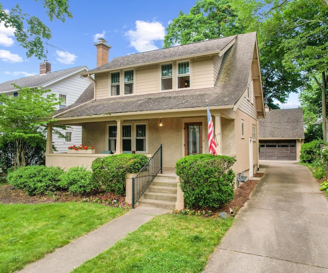 216 Kenwood Ave, Ann Arbor, MI 48103 - view of front facade featuring covered porch, stucco siding, a detached garage, a front yard, and roof with shingles