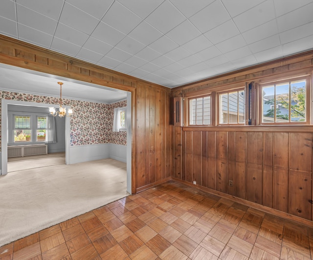 216 Kenwood Ave, Ann Arbor, MI 48103 - unfurnished room featuring a chandelier, plenty of natural light, wood walls, and radiator