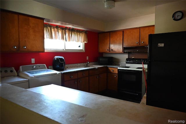 45225 Bemis Rd, Belleville, MI 48111 - kitchen with black appliances, separate washer and dryer, under cabinet range hood, brown cabinetry, and light countertops