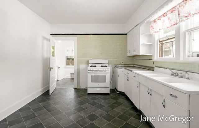 256 W Forest Ave, Muskegon, MI 49441 - kitchen featuring white gas stove, light countertops, white cabinetry, open shelves, and tasteful backsplash