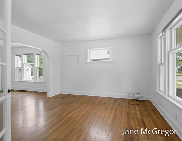256 W Forest Ave, Muskegon, MI 49441 - empty room featuring wood-type flooring, healthy amount of natural light, and arched walkways
