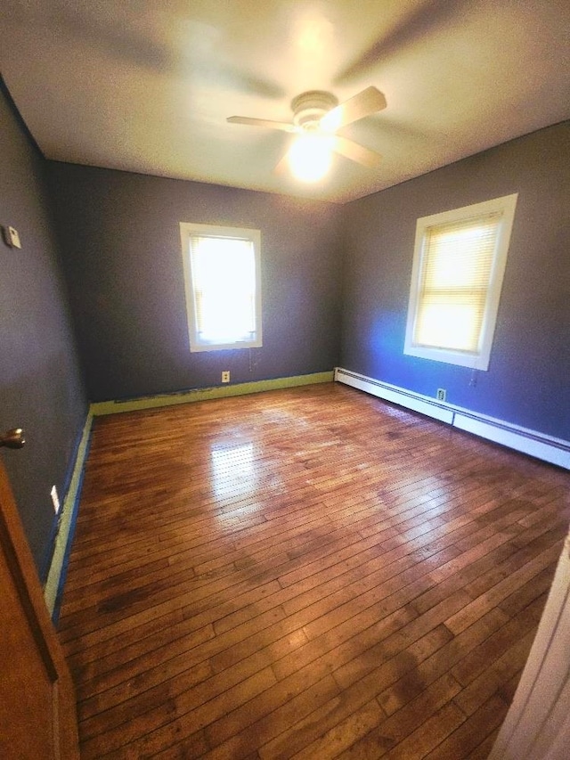 1308 W Broadway, Mount Pleasant, MI 48858 - empty room featuring a baseboard heating unit, ceiling fan, and hardwood / wood-style floors