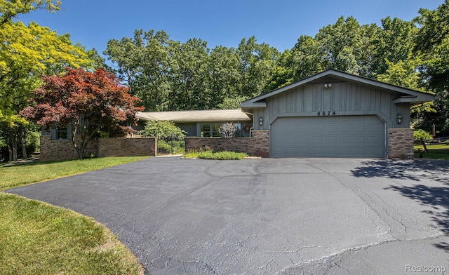 6674 Balmoral Ter, Clarkston, MI 48346 - view of front of home with asphalt driveway, brick siding, a garage, and board and batten siding