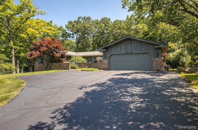 6674 Balmoral Ter, Clarkston, MI 48346 - view of front of property featuring asphalt driveway, board and batten siding, an attached garage, and brick siding
