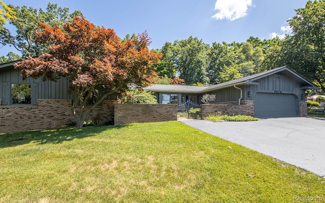 6674 Balmoral Ter, Clarkston, MI 48346 - view of front of house featuring board and batten siding, brick siding, asphalt driveway, a garage, and a front yard