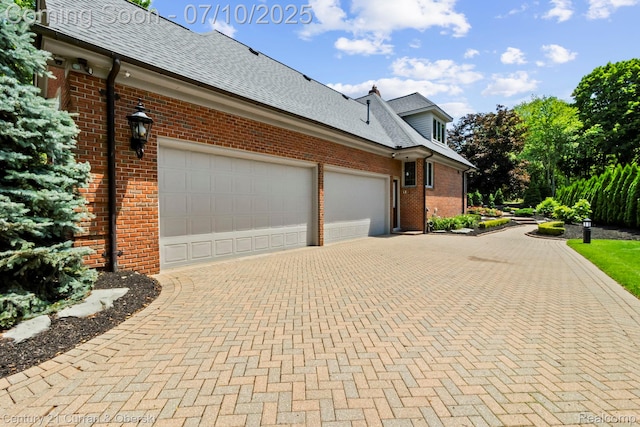 18878 Oak Leaf Ln, Northville, MI 48168 - view of side of home with brick siding, decorative driveway, an attached garage, and a shingled roof