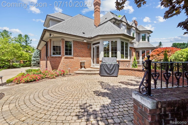 18878 Oak Leaf Ln, Northville, MI 48168 - rear view of house featuring brick siding, a chimney, roof with shingles, and a patio