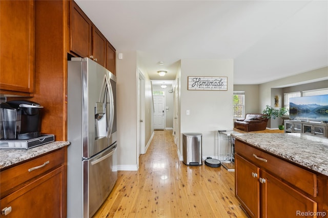 750 2nd St Unit 27, Wyandotte, MI 48192 - kitchen featuring stainless steel fridge with ice dispenser, light wood-style flooring, open floor plan, and light stone counters