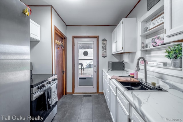6123 Lapeer Rd, Burton, MI 48509 - kitchen featuring stainless steel appliances, white cabinetry, light stone countertops, and ornamental molding