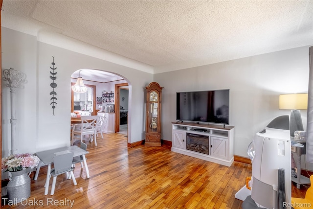 6123 Lapeer Rd, Burton, MI 48509 - living room with a textured ceiling, light wood-style floors, and arched walkways