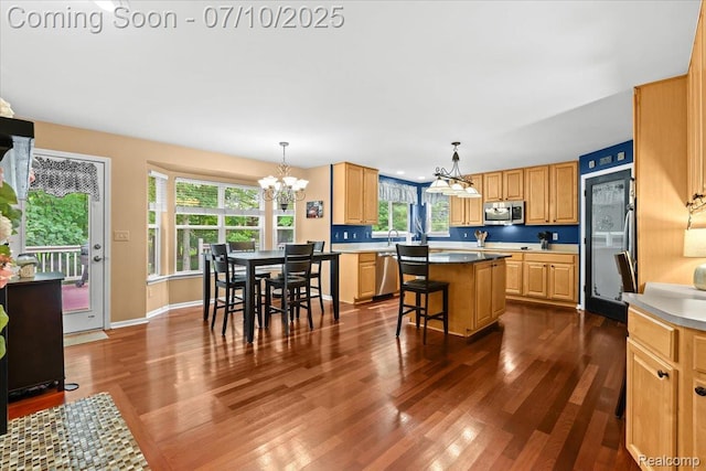 4583 Racewood Dr, Commerce Twp, MI 48382 - kitchen with a chandelier, stainless steel appliances, a center island, dark wood-type flooring, and a breakfast bar area