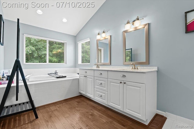 4583 Racewood Dr, Commerce Twp, MI 48382 - bathroom with double vanity, a garden tub, lofted ceiling, and wood finished floors