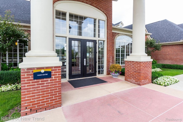 45929 Graystone Ln, Canton, MI 48187 - view of exterior entry with french doors, a shingled roof, brick siding, and a chimney
