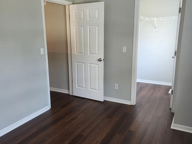 8270 Robins Ln, Battle Creek, MI 49014 - unfurnished bedroom featuring dark wood-type flooring, a closet, and a walk in closet