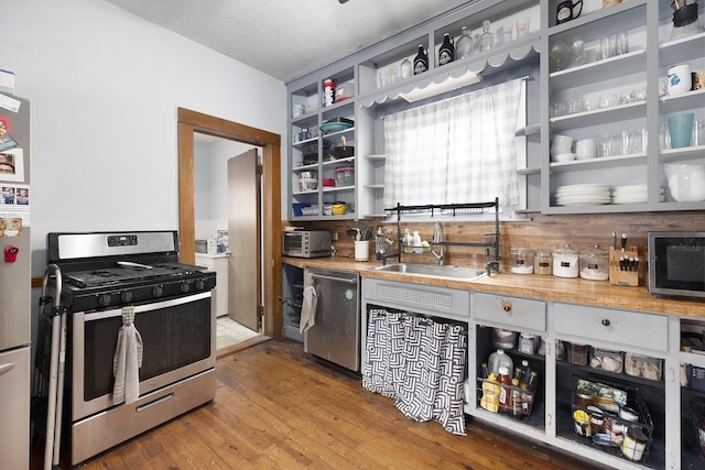 1607 Center Ave NE, Grand Rapids, MI 49505 - kitchen with appliances with stainless steel finishes, open shelves, wood-type flooring, and light countertops