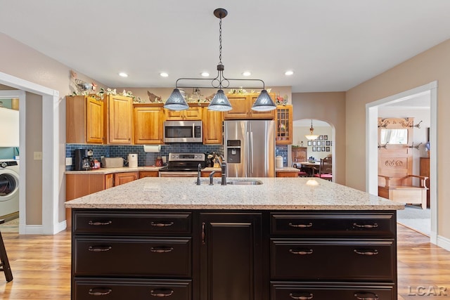 3224 Sand Creek Highway, Adrian, MI 49221 - kitchen featuring stainless steel appliances, a kitchen island with sink, light wood-type flooring, pendant lighting, and backsplash