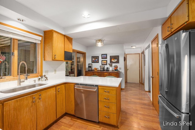 6636 E Riverwoods Ct NE, Rockford, MI 49341 - kitchen featuring appliances with stainless steel finishes, a peninsula, light countertops, and brown cabinets