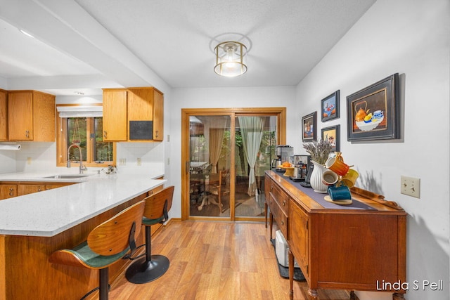 6636 E Riverwoods Ct NE, Rockford, MI 49341 - kitchen with light wood-style floors, a breakfast bar, a peninsula, brown cabinets, and backsplash