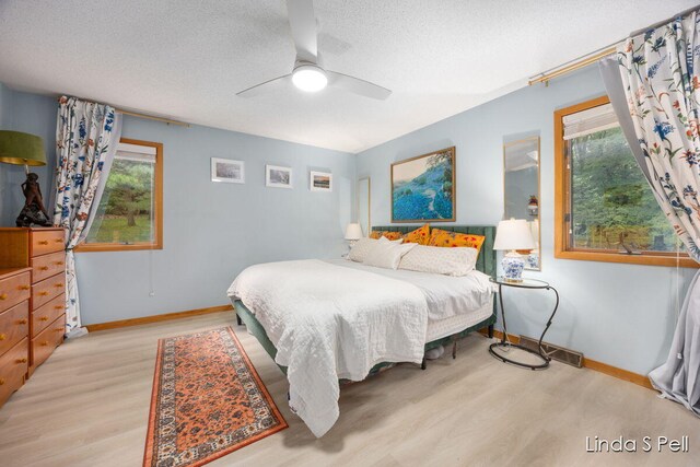6636 E Riverwoods Ct NE, Rockford, MI 49341 - bedroom with a textured ceiling, multiple windows, wood finished floors, and ceiling fan