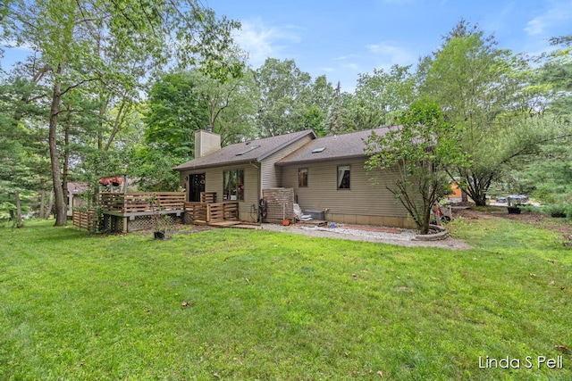 6636 E Riverwoods Ct NE, Rockford, MI 49341 - rear view of house with a chimney, a yard, a wooden deck, and a shingled roof