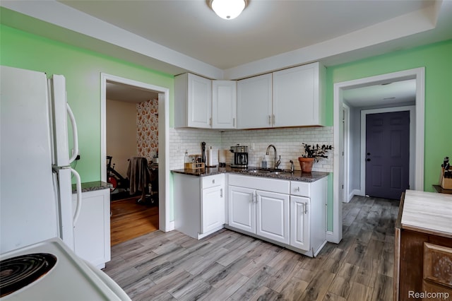 1217 E Madge Ave, Hazel Park, MI 48030 - kitchen featuring freestanding refrigerator, white cabinetry, tasteful backsplash, light wood-type flooring, and dark stone countertops