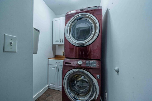 4433 Elm St, New Era, MI 49446 - washroom featuring stacked washer / dryer, cabinet space, and dark wood-style floors