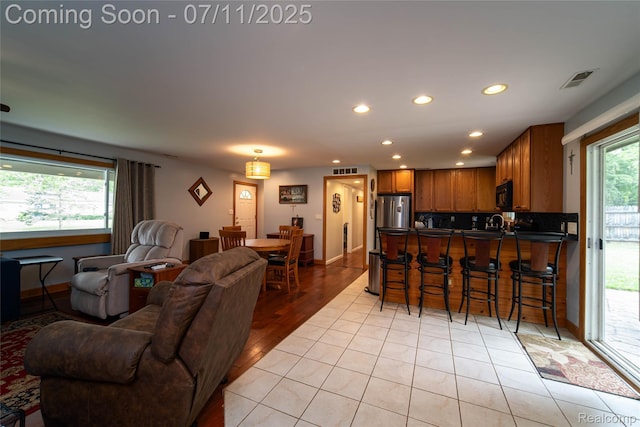 3238 Homestead Dr, Waterford, MI 48329 - kitchen featuring stainless steel fridge, open floor plan, black microwave, a kitchen bar, and dark countertops