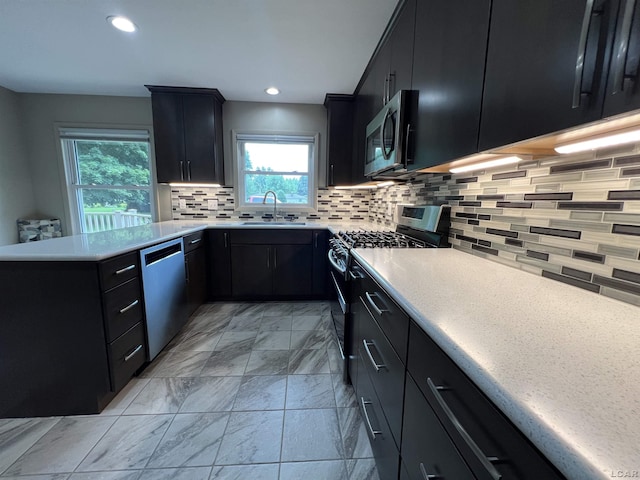 2244 Shannon Dr, Adrian, MI 49221 - kitchen featuring appliances with stainless steel finishes, dark cabinetry, light marble finish floors, decorative backsplash, and light countertops