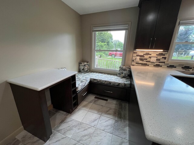 2244 Shannon Dr, Adrian, MI 49221 - kitchen featuring dark cabinetry, tasteful backsplash, light marble finish floors, and a peninsula