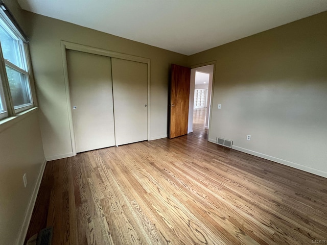 2244 Shannon Dr, Adrian, MI 49221 - unfurnished bedroom featuring wood finished floors, multiple windows, and a closet