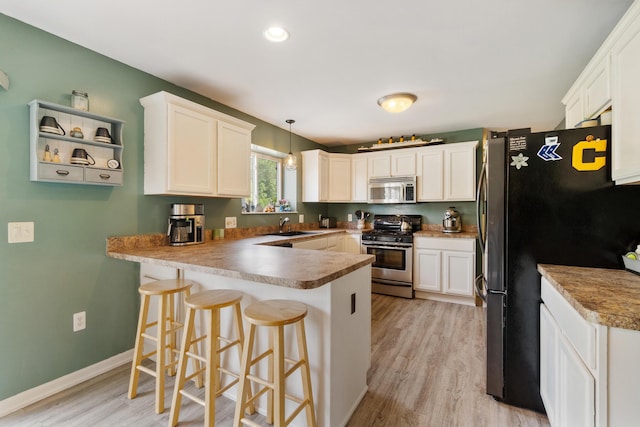 127 Ridgeview Ct, Grass Lake, MI 49240 - kitchen with stainless steel appliances, a peninsula, light wood finished floors, white cabinetry, and recessed lighting