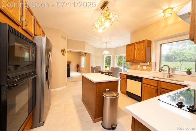 24145 Windridge Ln, Novi, MI 48374 - kitchen featuring black appliances, a chandelier, brown cabinets, a kitchen island, and hanging light fixtures