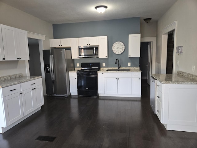 7 Hewitt St, Quincy, MI 49082 - kitchen featuring stainless steel appliances, dark wood finished floors, white cabinets, and light stone counters