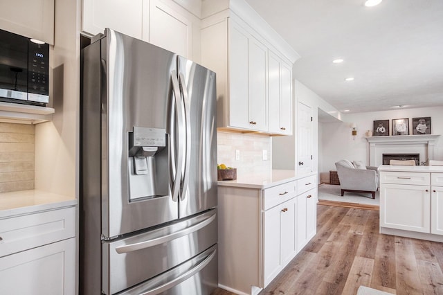 5665 Koster Dr SW, Wyoming, MI 49418 - kitchen with stainless steel fridge, light wood-style flooring, open floor plan, white cabinetry, and backsplash