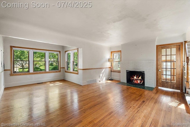 524 Oakland Ave, Birmingham, MI 48009 - unfurnished living room with a brick fireplace and hardwood / wood-style floors