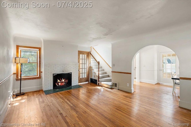 524 Oakland Ave, Birmingham, MI 48009 - unfurnished living room featuring hardwood / wood-style flooring, arched walkways, a fireplace, and stairway