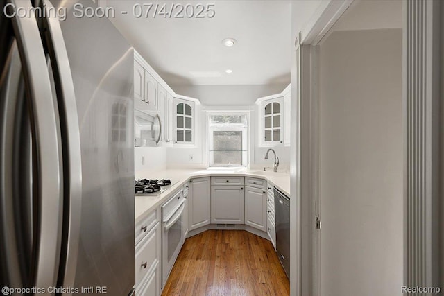 524 Oakland Ave, Birmingham, MI 48009 - kitchen featuring appliances with stainless steel finishes, glass insert cabinets, white cabinetry, light wood-style floors, and recessed lighting