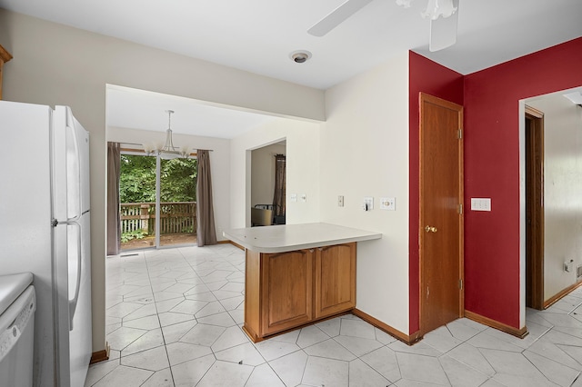 7906 N 43rd St, Augusta, MI 49012 - kitchen with white appliances, a peninsula, light countertops, a chandelier, and brown cabinetry