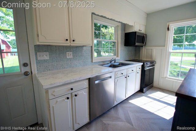 4201 N Burkhart Rd, Howell, MI 48855 - kitchen featuring stainless steel appliances, white cabinets, plenty of natural light, and a decorative wall