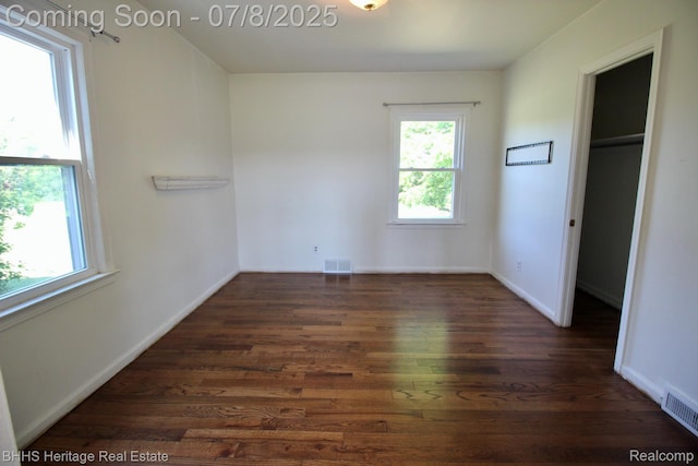 4201 N Burkhart Rd, Howell, MI 48855 - unfurnished bedroom featuring wood finished floors, multiple windows, and a walk in closet