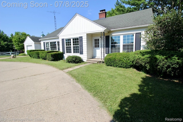 4201 N Burkhart Rd, Howell, MI 48855 - view of front facade featuring a front lawn, a chimney, board and batten siding, and roof with shingles