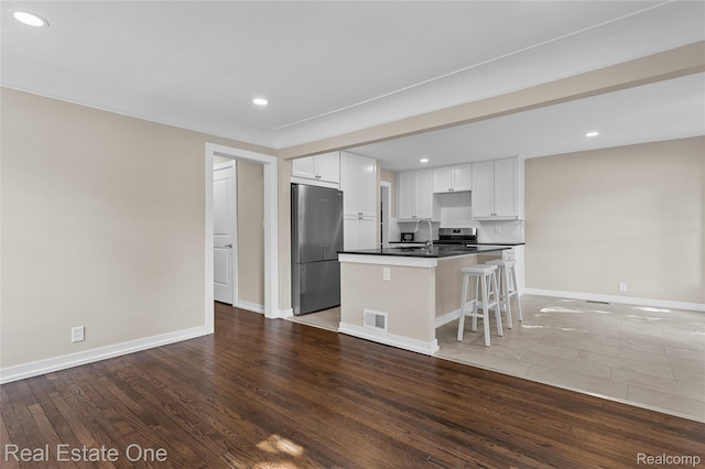 1746 N Lafayette St, Dearborn, MI 48128 - kitchen featuring appliances with stainless steel finishes, dark countertops, white cabinetry, recessed lighting, and a center island with sink