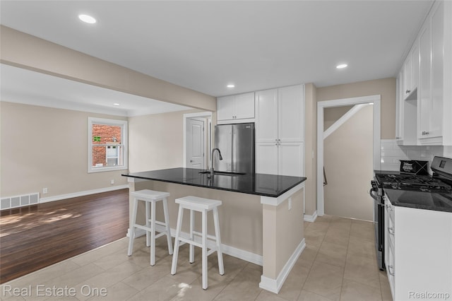 1746 N Lafayette St, Dearborn, MI 48128 - kitchen featuring appliances with stainless steel finishes, backsplash, a breakfast bar, white cabinetry, and dark countertops