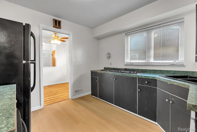 1885 Pelham St, Dearborn, MI 48124 - kitchen featuring freestanding refrigerator, light wood-style floors, dark countertops, stainless steel gas stovetop, and dark cabinetry