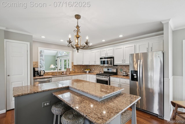 378 Fruitdale Ln, Pinckney, MI 48169 - kitchen with appliances with stainless steel finishes, ornamental molding, a kitchen island, white cabinets, and dark wood-style flooring