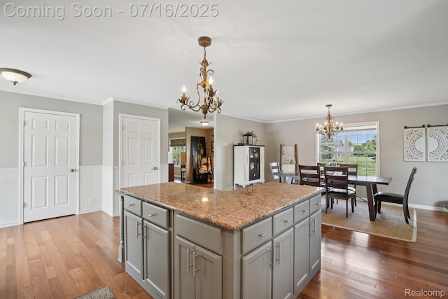 378 Fruitdale Ln, Pinckney, MI 48169 - kitchen featuring gray cabinets, a chandelier, wood finished floors, a center island, and crown molding