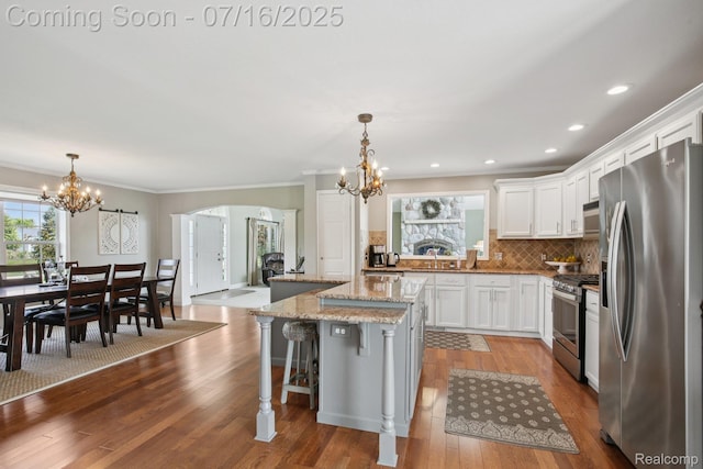 378 Fruitdale Ln, Pinckney, MI 48169 - kitchen featuring stainless steel appliances, a chandelier, a kitchen island, tasteful backsplash, and ornamental molding