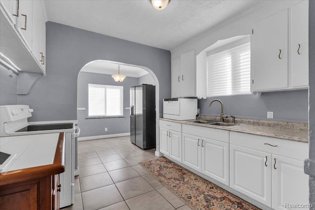 18040 Indiana St, Detroit, MI 48221 - kitchen featuring stainless steel fridge, white range with electric stovetop, white cabinets, arched walkways, and light tile patterned floors