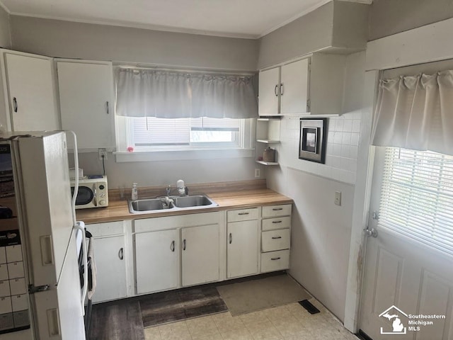 402 W Sixth St, Monroe, MI 48161 - kitchen with light countertops, freestanding refrigerator, ornamental molding, white cabinetry, and washer / clothes dryer
